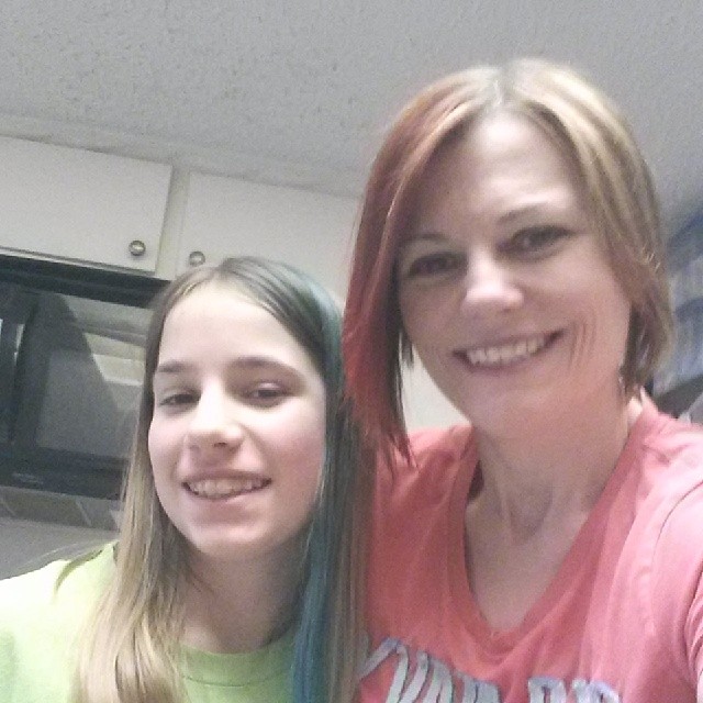 a woman with red hair and green hair next to a little girl