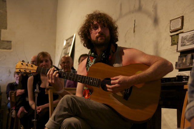 a man playing a guitar next to women