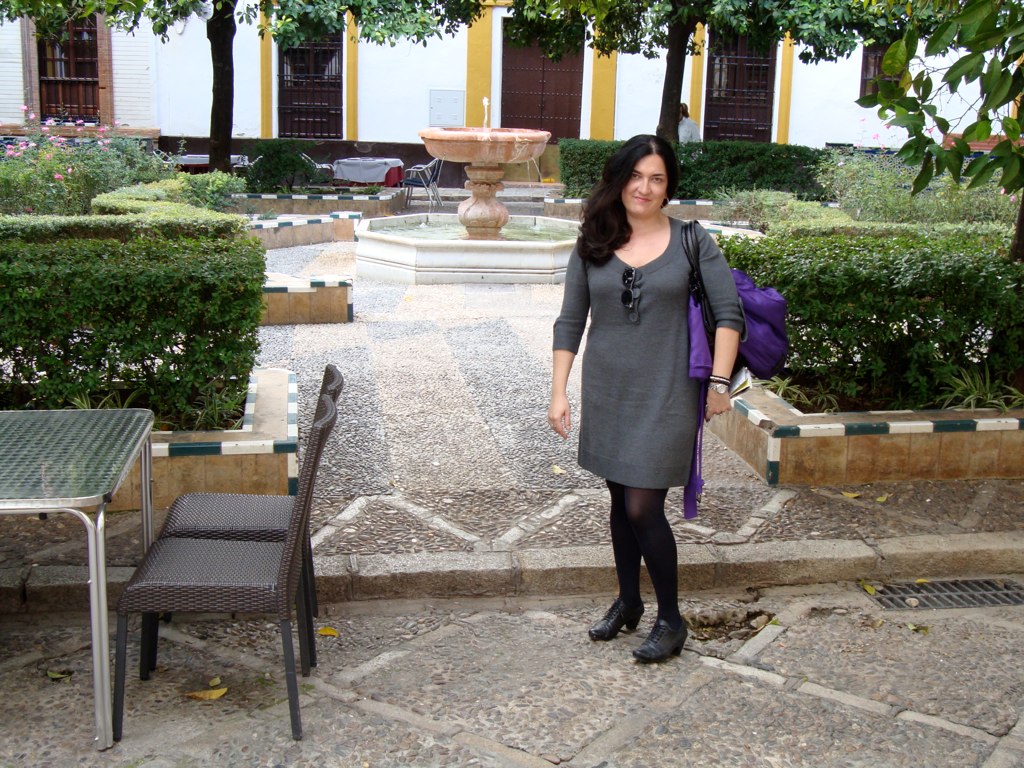 the woman stands in the courtyard with her backpack on