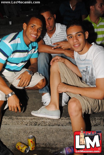three young men sit on steps and look at the camera