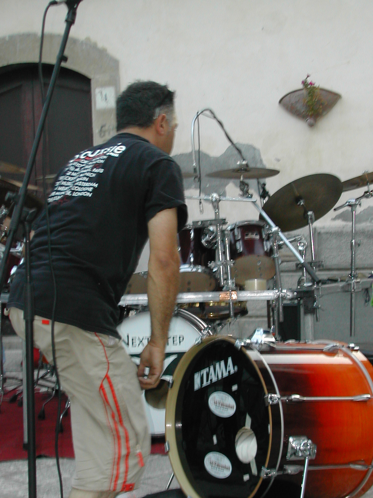 man standing behind a drum set that is in front of a microphone