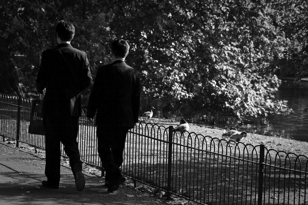 black and white pograph of two men standing near a fence