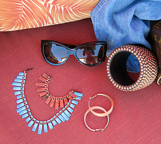 some jewellery, sunglasses, and two pairs of shoes sitting on a pink surface