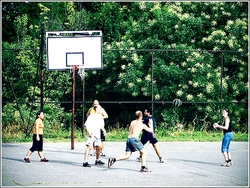 a group of young people playing basketball with one trying to block the s