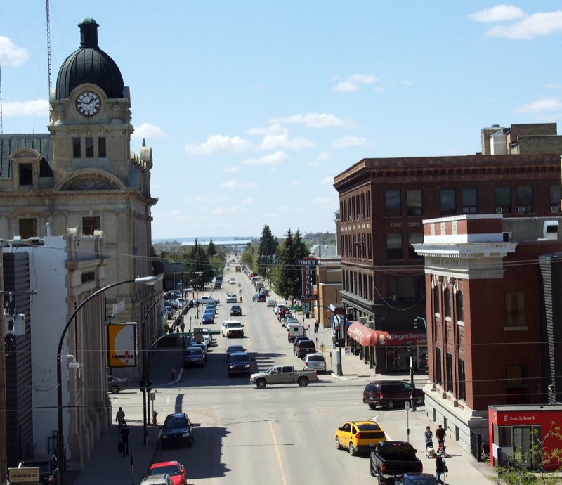 an empty street with some people walking and cars on it