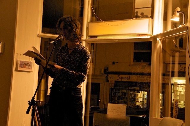 a woman standing in front of a microphone holding a book