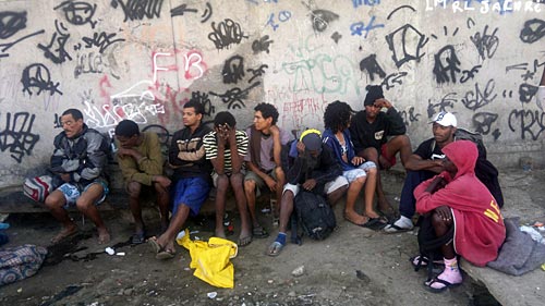 a group of men sitting around each other next to a wall covered in graffiti