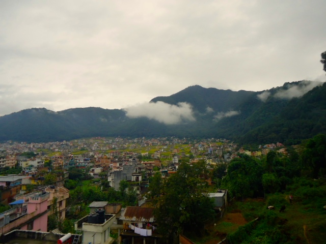 view of a town nestled between mountains and cloudy skies