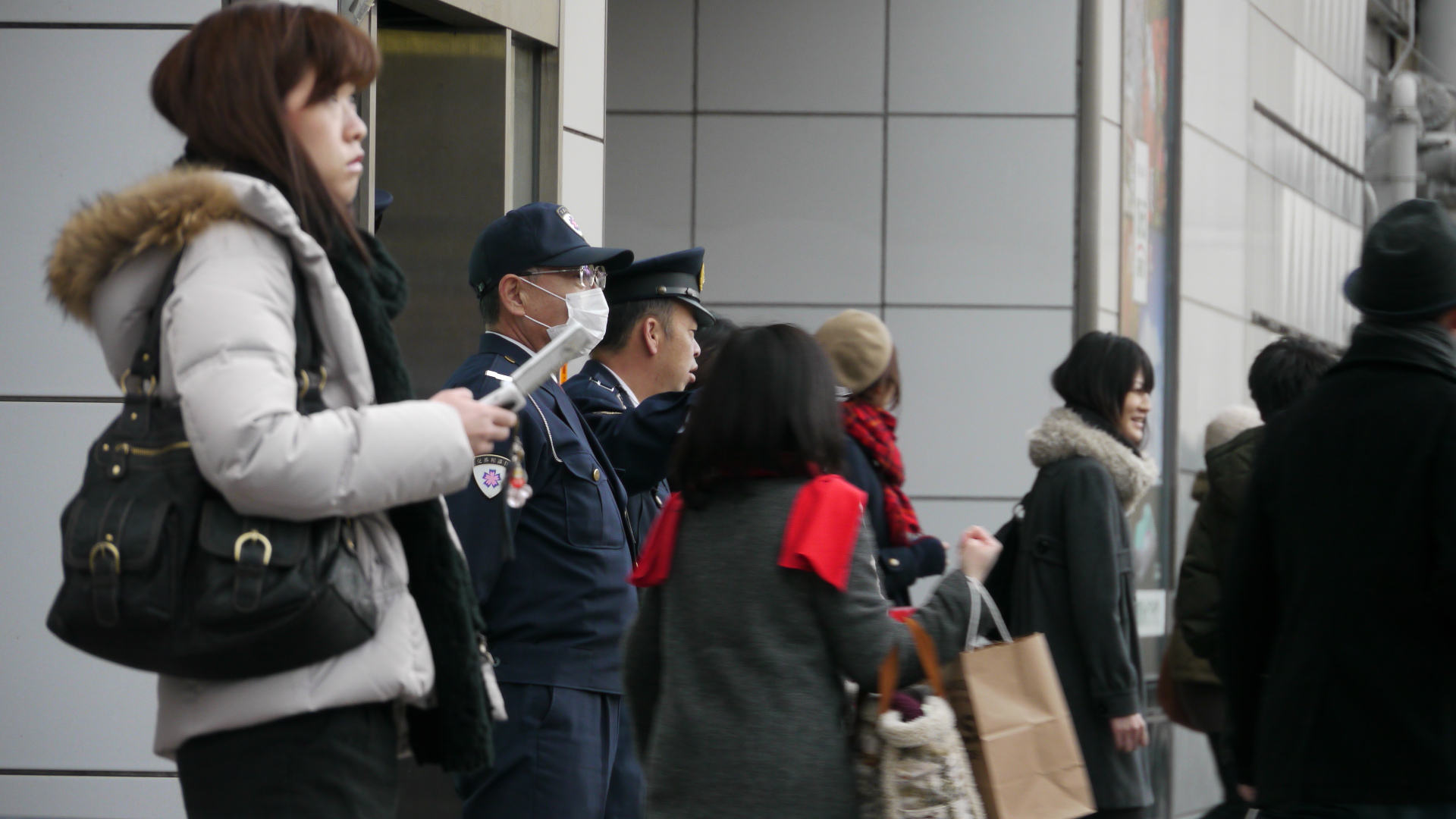 people walking on sidewalk with luggage bags near a building