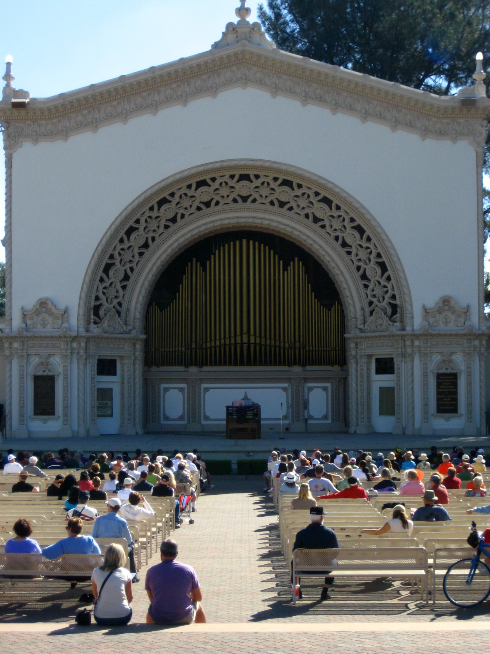 an outdoor audience sits on benches to watch a band perform