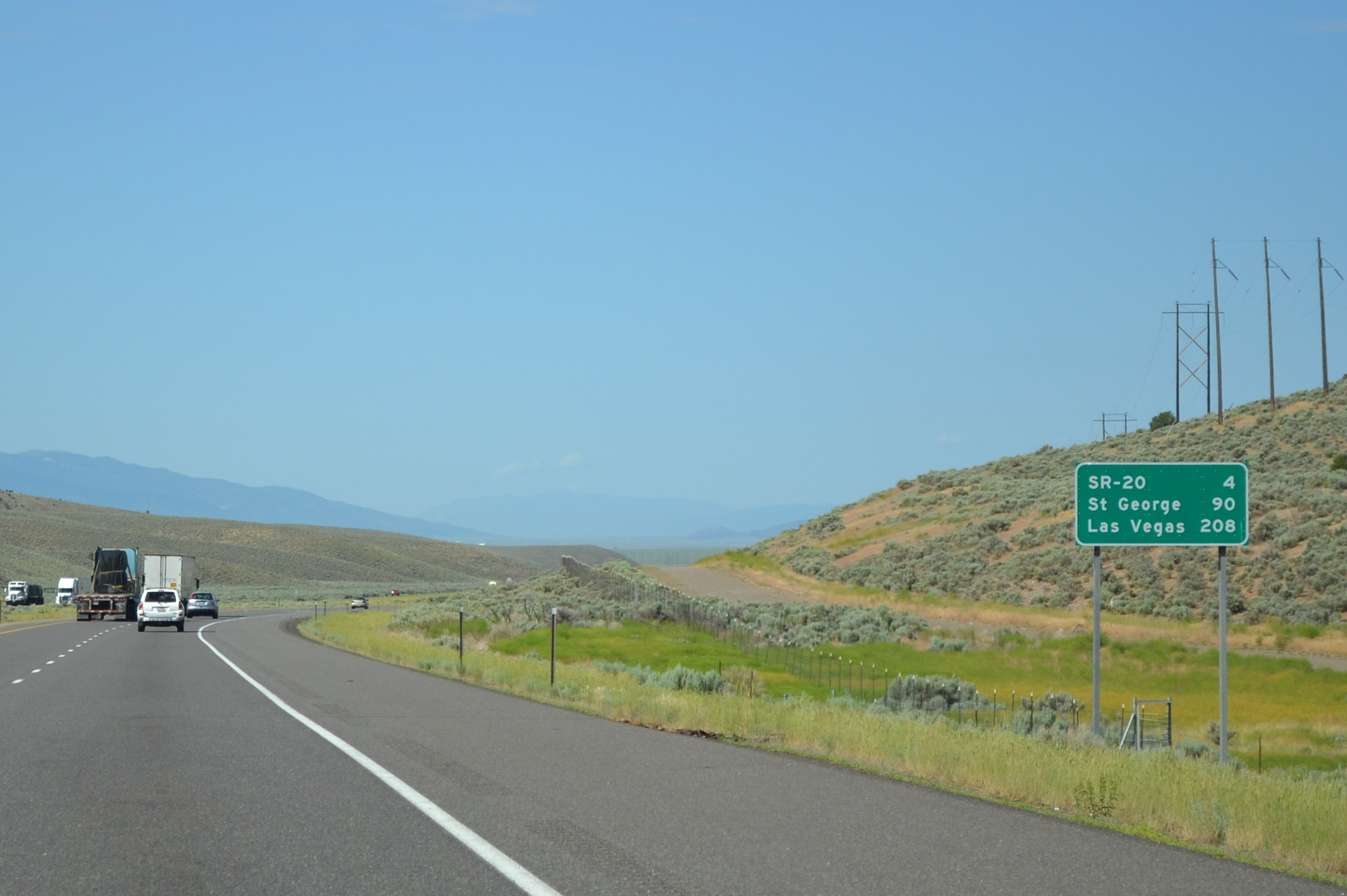 a big green highway sign in a grassy area