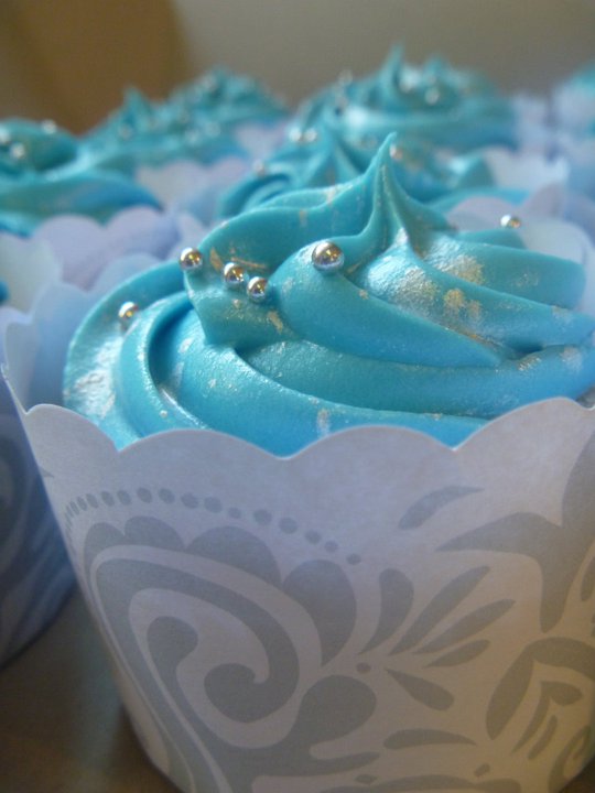 many blue cupcakes in decorative paper cups