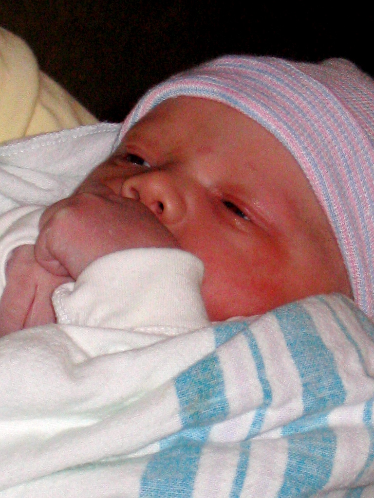 a baby laying in the arms of a man wearing a beanie