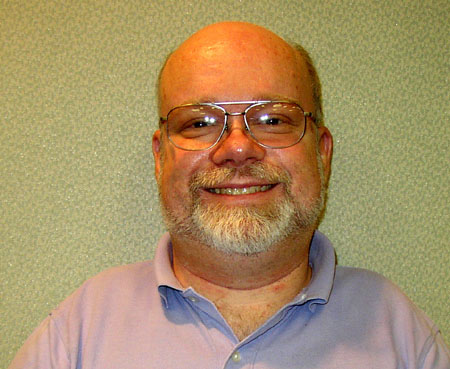 a man in glasses smiling for a po