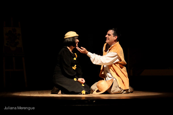 two men sit on a stage, talking