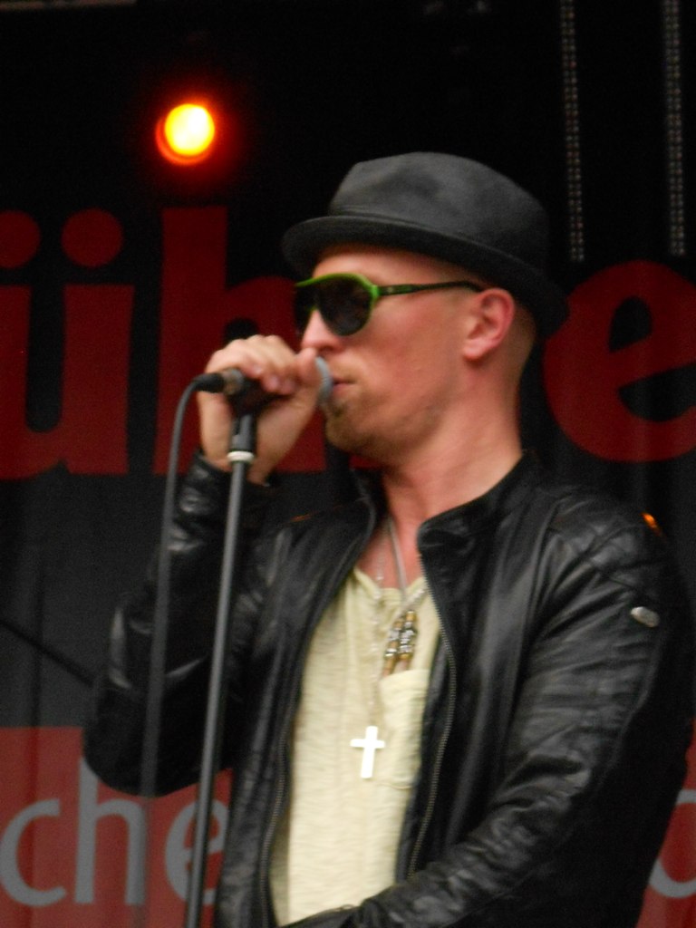 the man with black glasses sings into his microphone