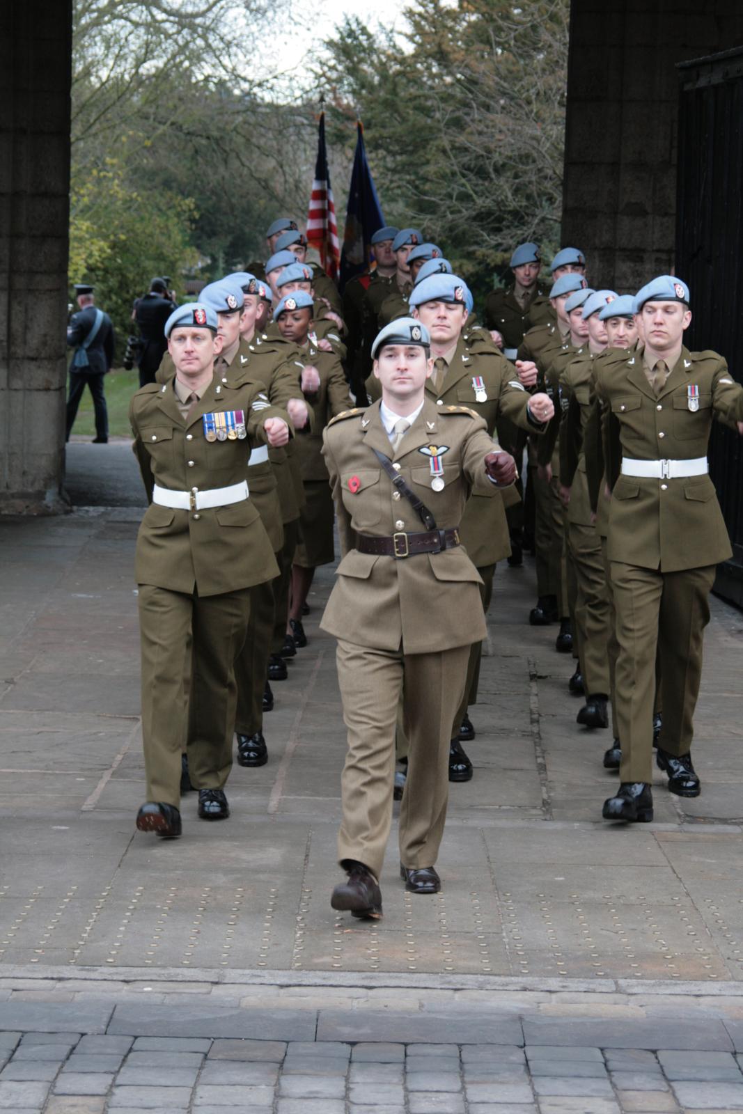 men in uniforms are walking on a brick walkway