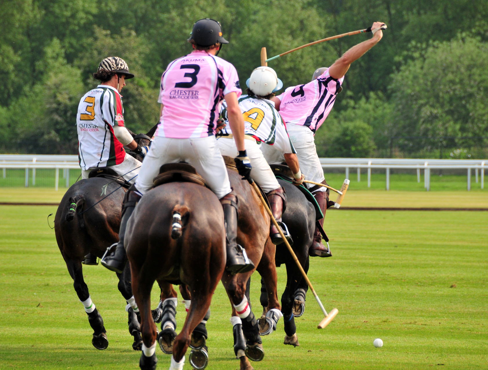 four men are competing in a polo match