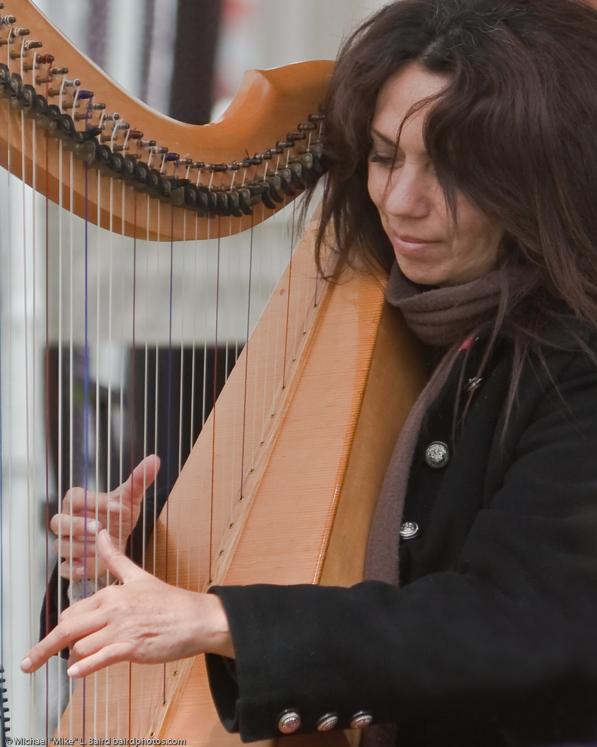 a woman holding a long harp and wearing a scarf