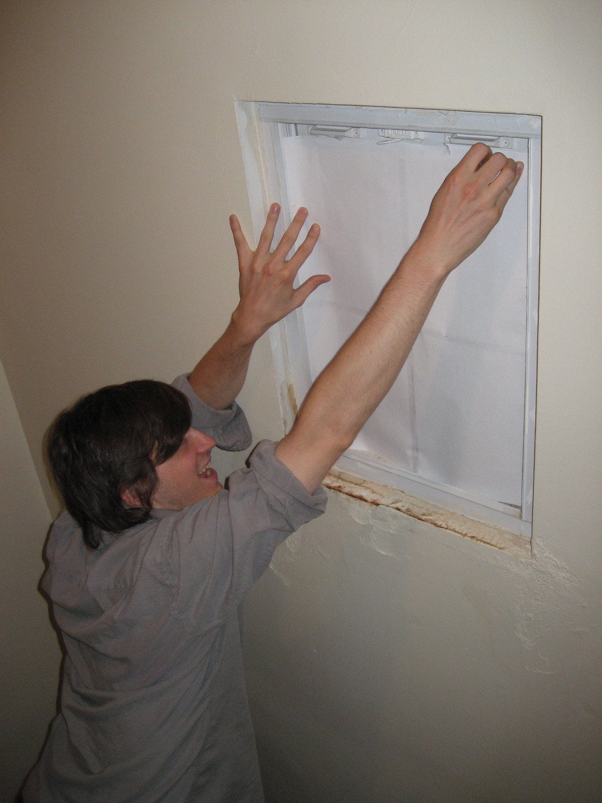 a man hangs a piece of white paper on the wall