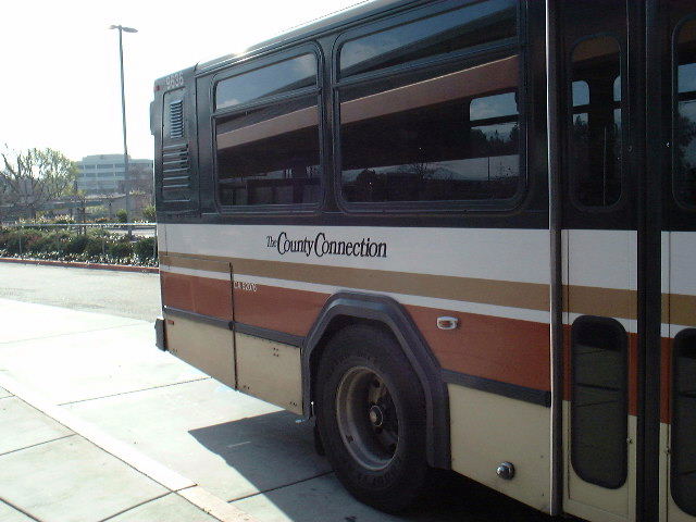 an open city bus parked on the side of the road