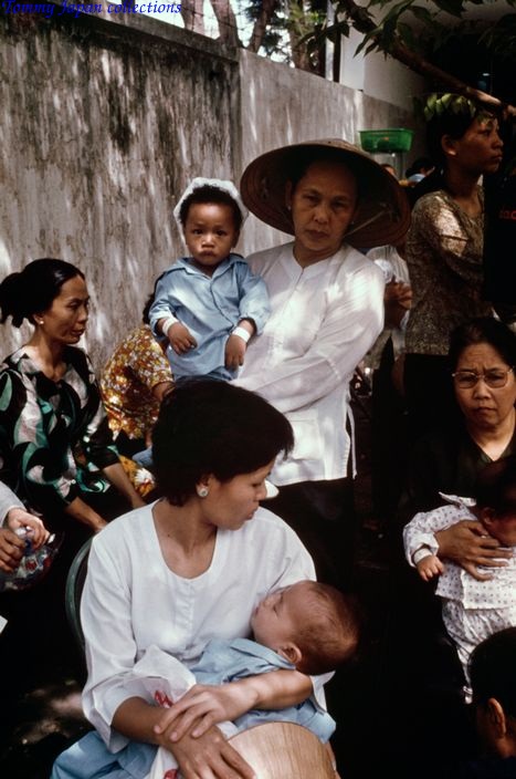 many women and children gathered around one woman holding a baby