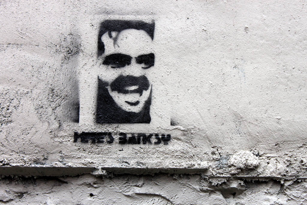 a graffiti on the side of a building shows a smiling man