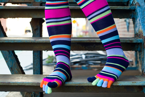 a person wearing brightly colored striped socks and sitting on a step