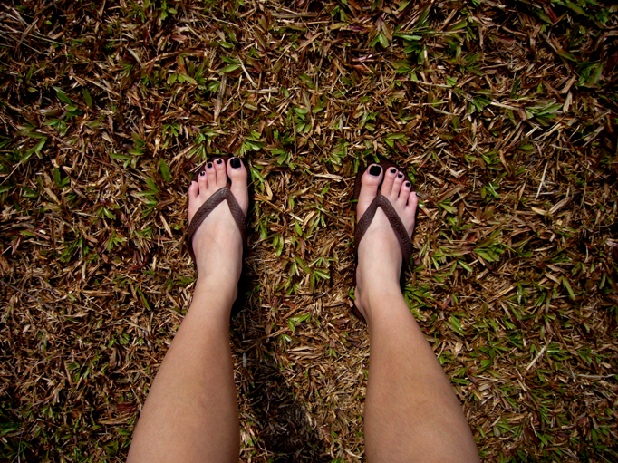 a person with black nails and a bare toe in the grass