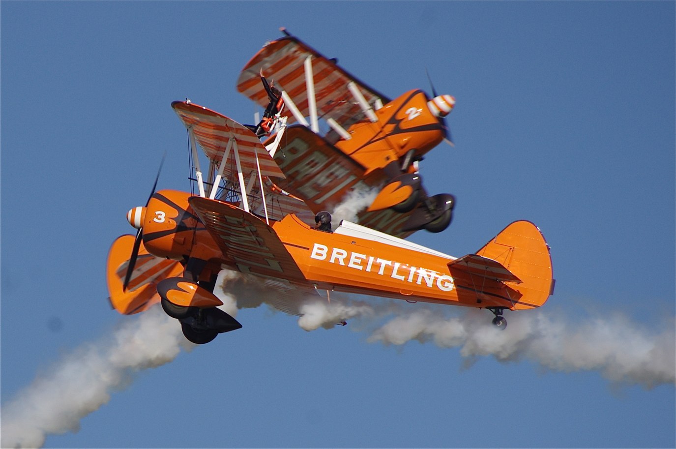 an orange plane is performing in a stunt in the air