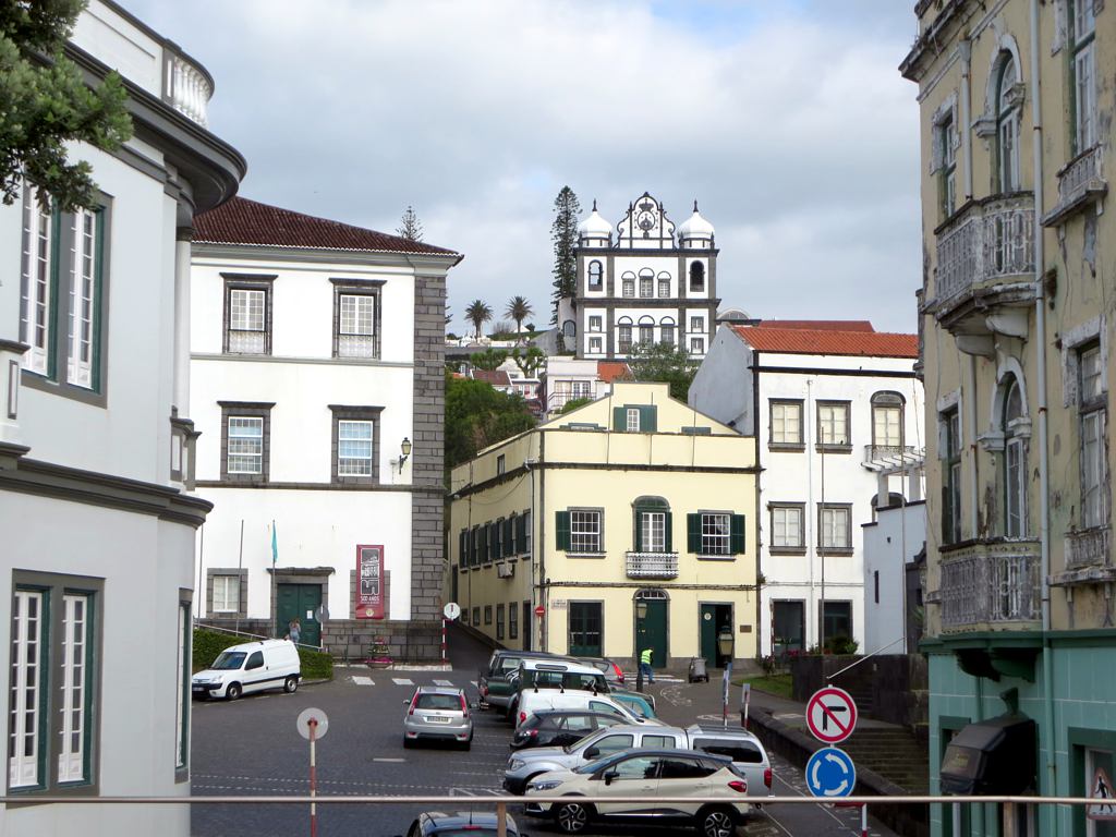 cars drive through a wide city street lined with old buildings