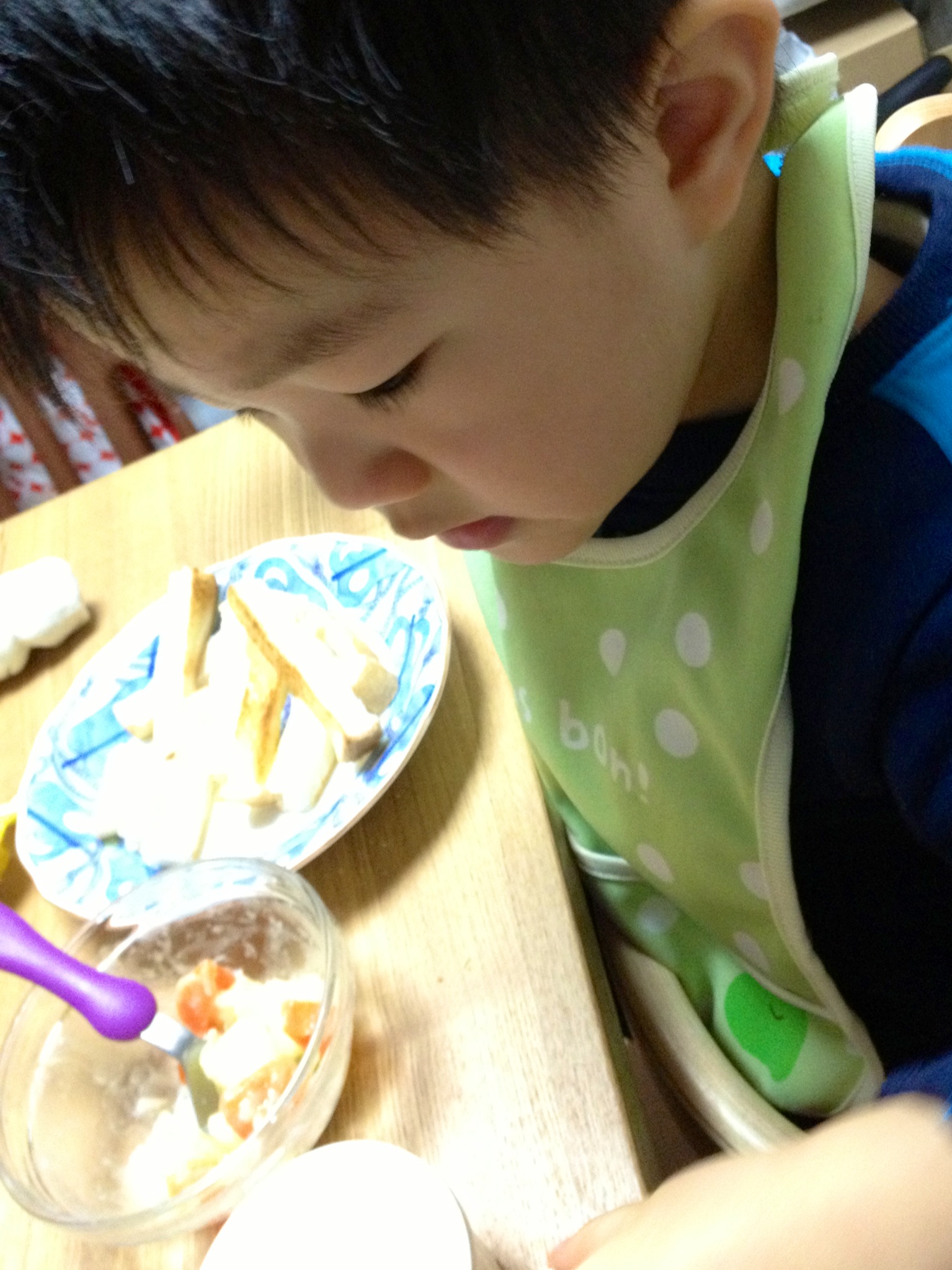 small child at a wooden table eating food