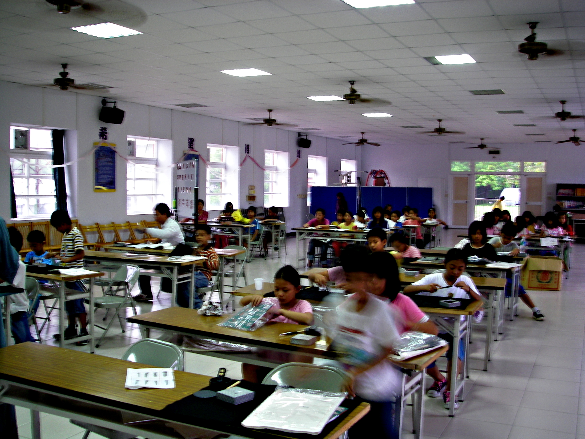 a classroom with many tables and desks full of students