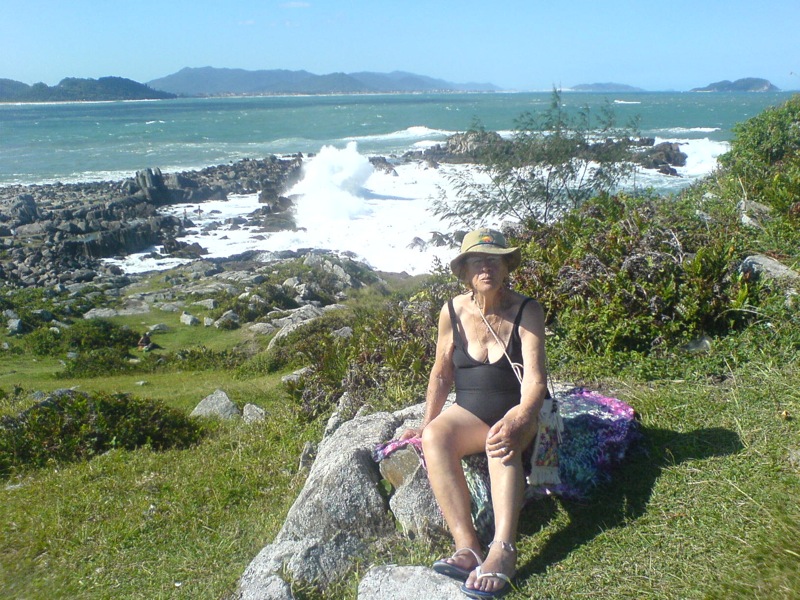 a woman sitting on a rock near the ocean