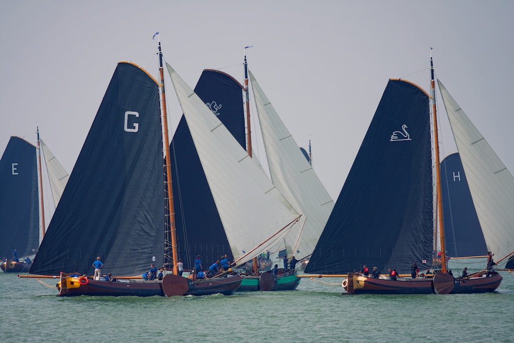 three large sail boats with sails on the water