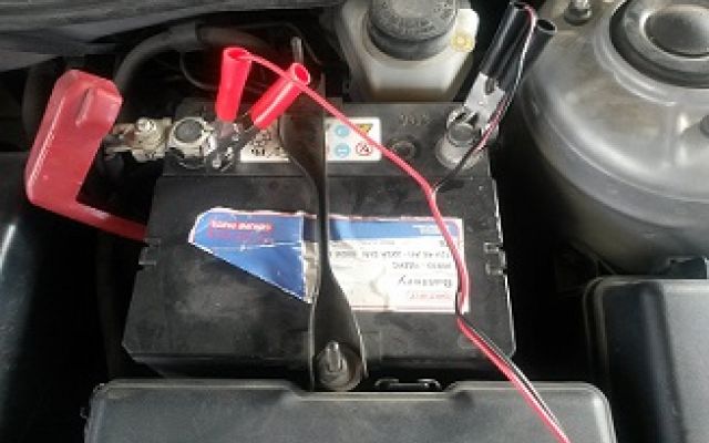 a car battery with wires and some electronic devices