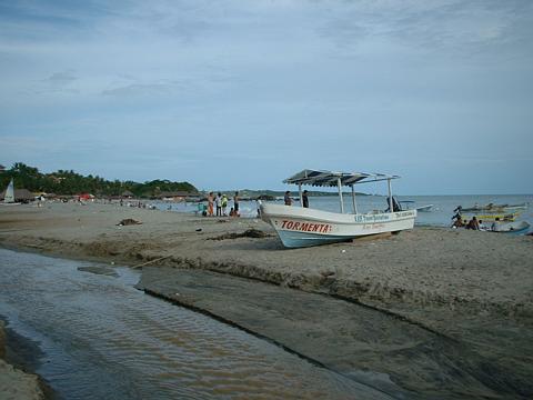 a small boat sits on the shore in front of people
