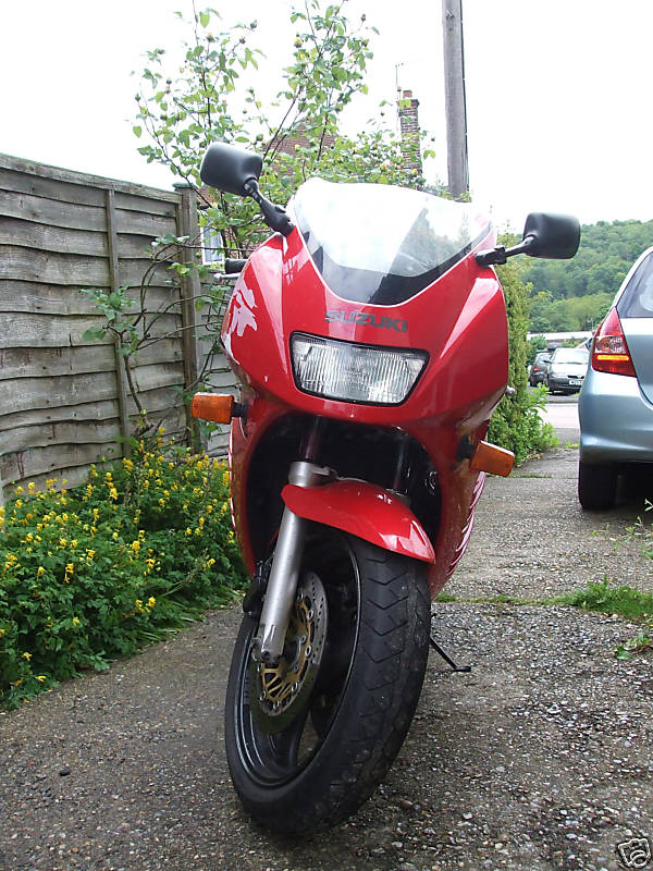 a red motorcycle parked on top of a gravel road