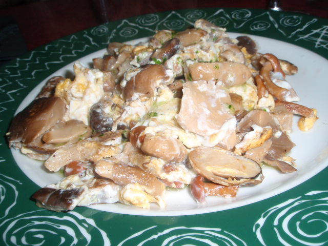 a pile of clams and shells with a small glass of wine