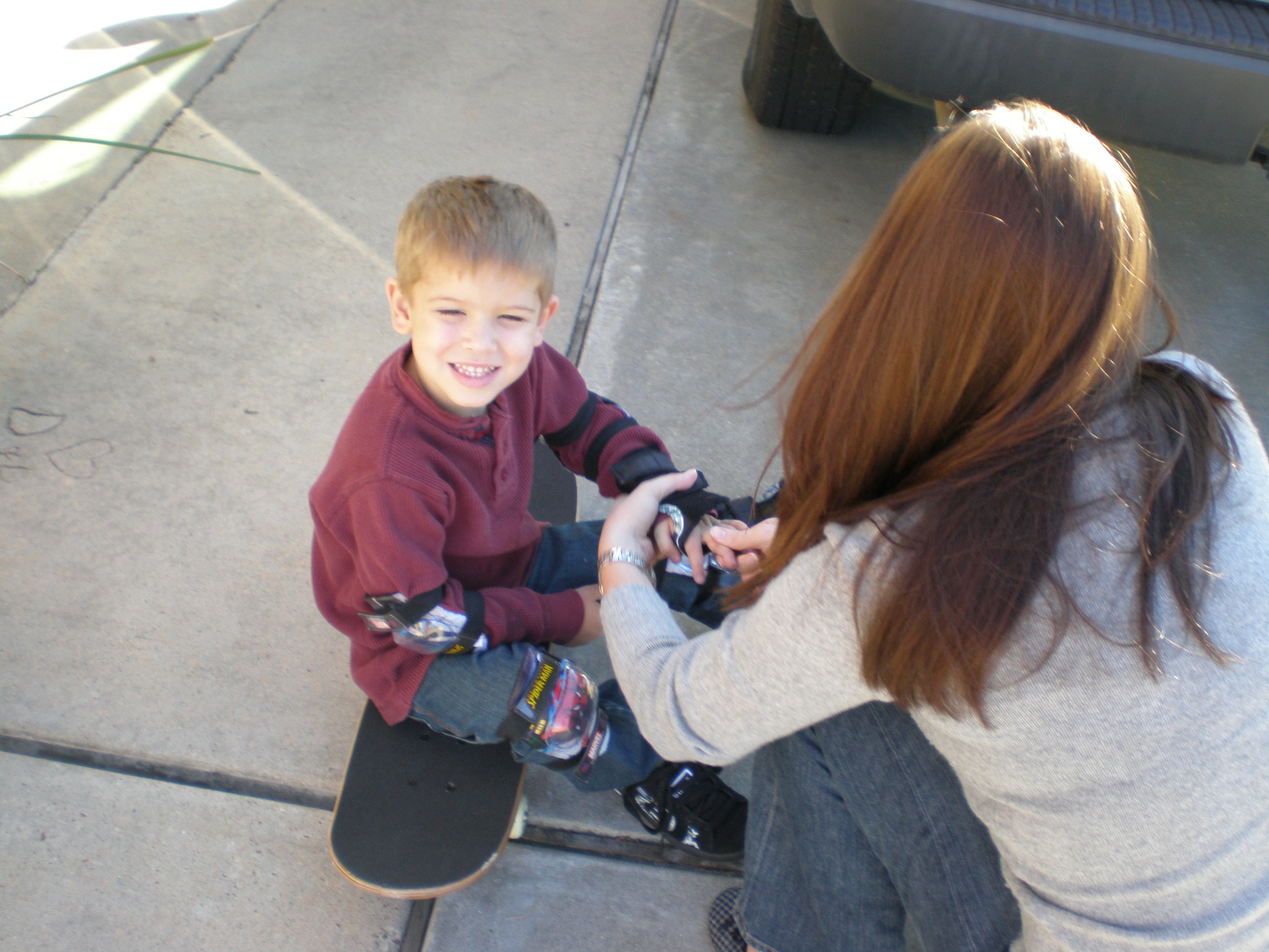 a woman showing a boy how to ride a skateboard