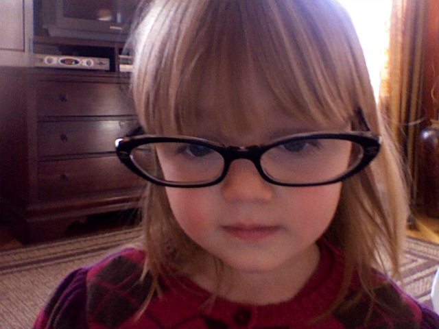 a little girl is wearing glasses for the camera