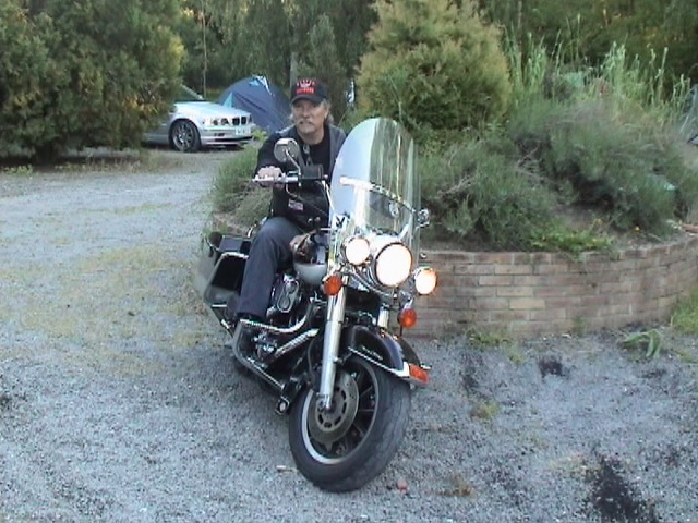 a man riding on the back of a motorcycle on a gravel road
