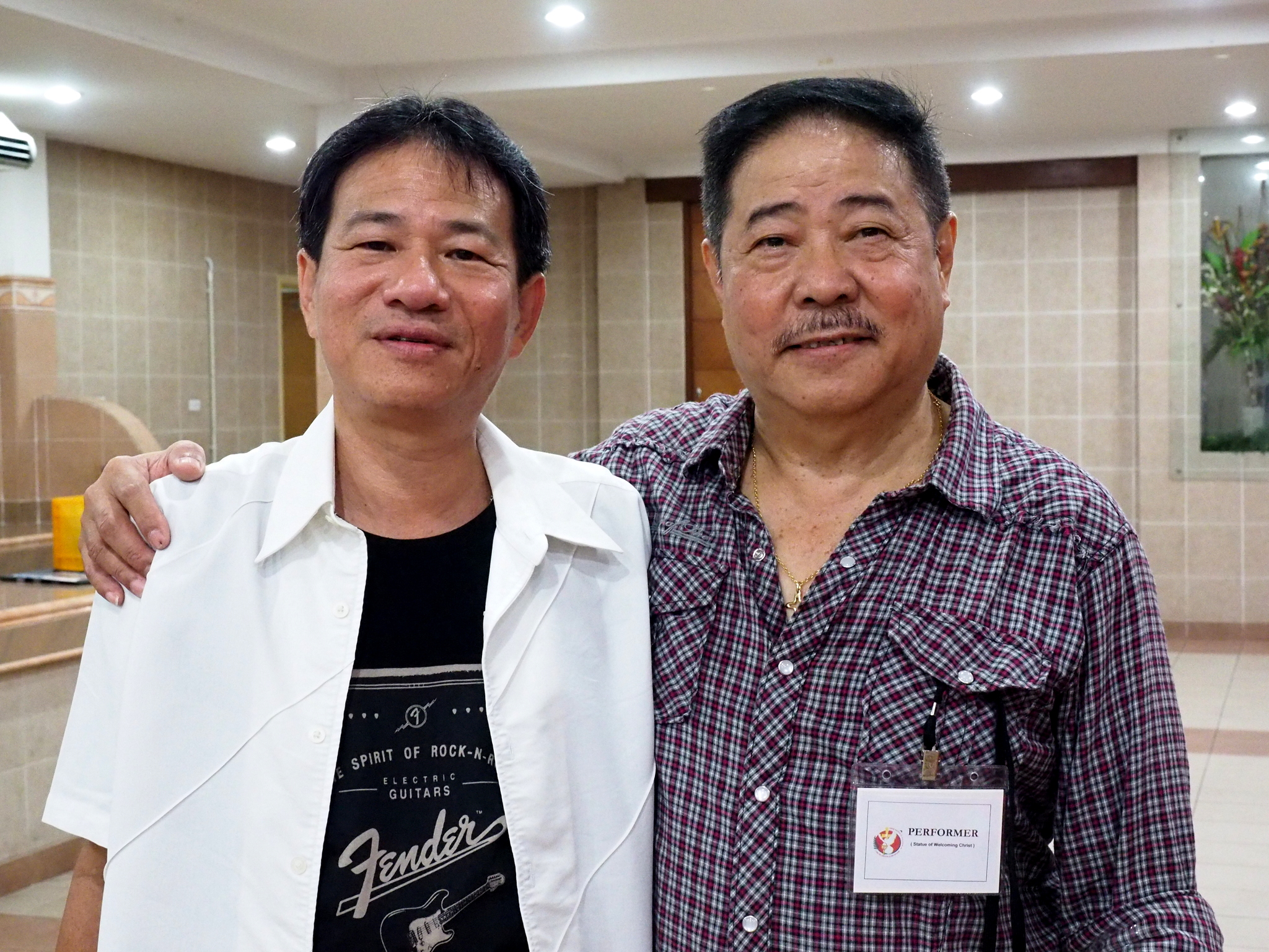 two men are posing for a picture in a hall