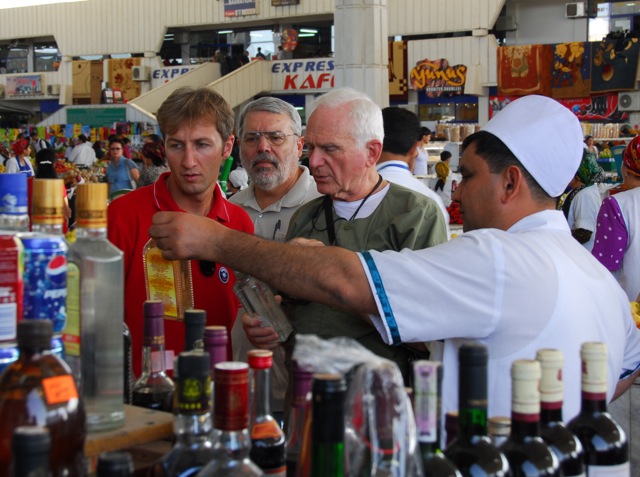 several people standing near a bar lined with bottles