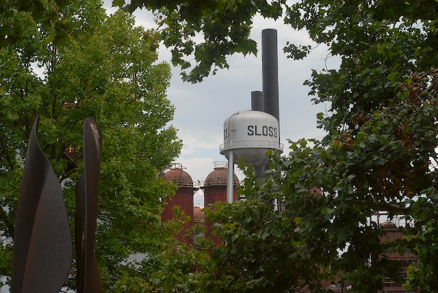 an industrial building in the background, with trees around it