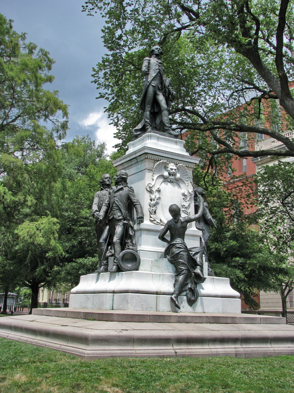 a monument of a person seated on a horse and other figures standing in the grass