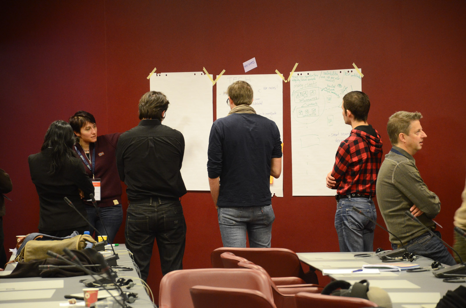 people stand around a conference room table with various papers on them