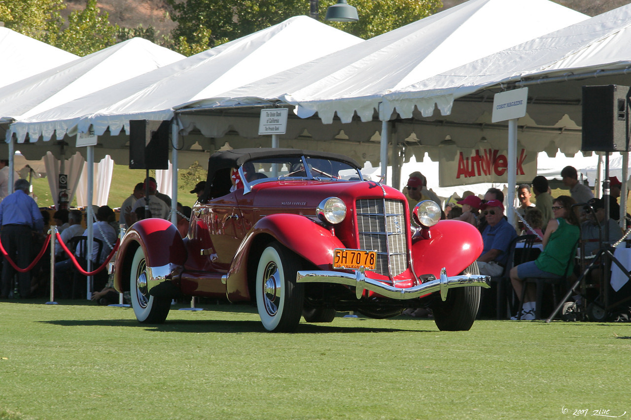 an old time car sits on display under tents at an event