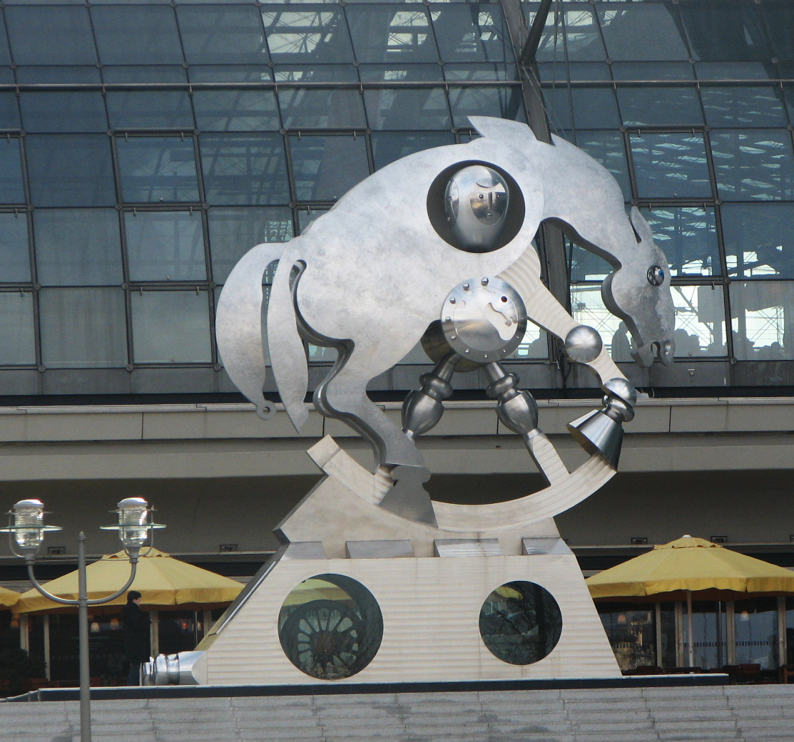 a large sculpture with an animal in front of a glass building