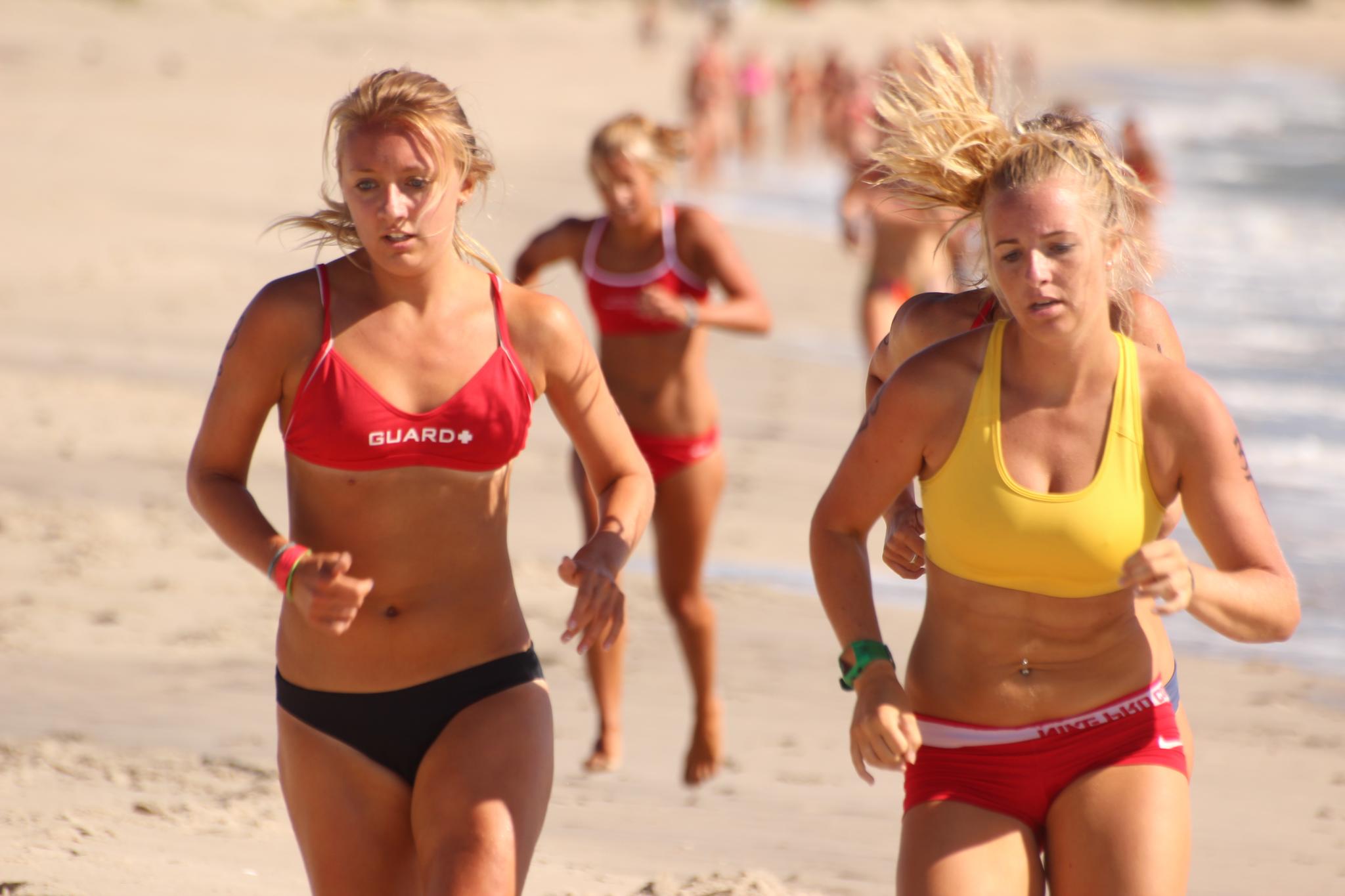 two young women are running along the beach together